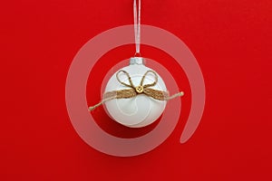 White christmas glass ball hanging with red background. New Year decoration. Winter Holiday concept. Minimal style