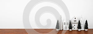 White Christmas house decor with trees on a wood shelf against a white wall banner background