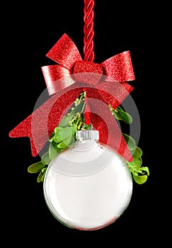 White Christmas ornament hanging by red ribbon rope with the bauble surrounded with green mistletoe