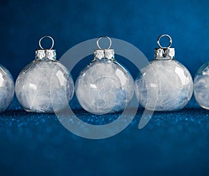 White christmas ornaments on dark blue glitter background with space for text.