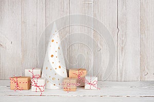 White Christmas tree decor on a shelf with rustic brown and white gift boxes against a grey wall