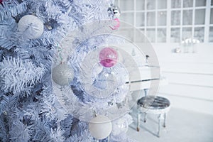 White Christmas tree decorated with silver and pink ornaments at the piano background.Winter scene. New Year decoration