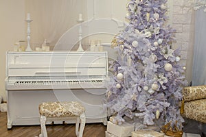 White Christmas tree decorated with silver and pink ornaments at the piano background.Winter scene. New Year decoration.Xmas