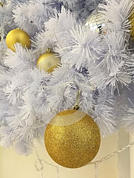 White Christmas tree decoration closed up glitter golden ball ornaments with white tinsel background