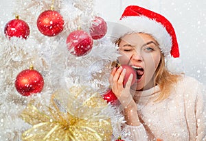 Woman in snow. White christmas tree red balls. Beautiful Woman in Santa Hat at Home. We wish you a merry christmas tree