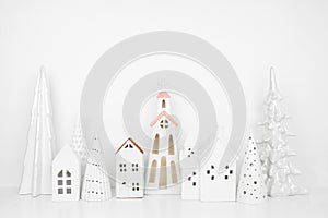White Christmas village decor on a shelf against a white wall background