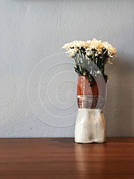 White chrysanthemum flower in beautiful vase on the wooden table with cement background.
