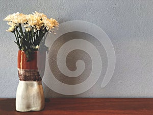 White chrysanthemum flower in beautiful vase on the wooden table with cement background.