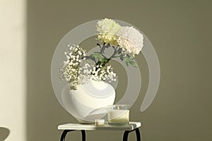 White chrysanthemums and gypsophila flower in white vase on gray interior. Minimalist still life. Light and shadow nature