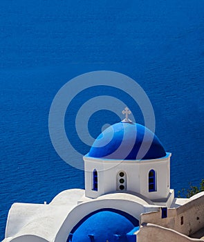 White church with blue dome against blue sea background. Oia Santorini, Greece