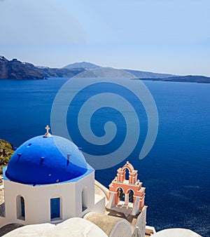 White church with blue dome against blue sea and sky background. Oia Santorini, Greece