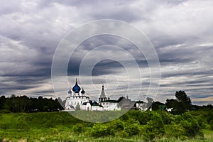 White church with blue domes under a stormy sky.