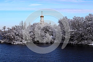 White Church on river in winter, trees covered with ice and snow. Winter landscape, Christian church