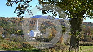 White church at stowe framed by tree and a hill with fall foliage