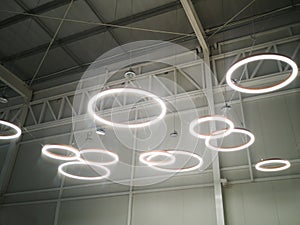 White circular ring shaped lamps hang under a concrete ceiling