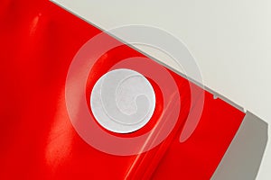 White circular sticker on red poly mailer envelope with natural shadow