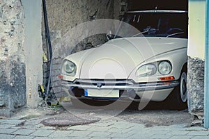 White Citroen vintage car parked in old town arch of a brick building side view