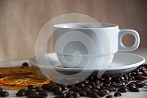 White classic Cup and saucer on the table, roasted coffee beans and dried orange
