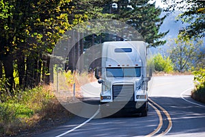 White classic semi truck big rig on winding sunny road