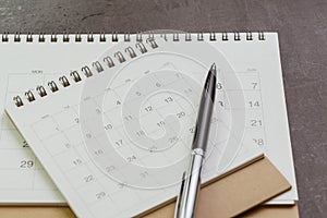 White clean calendar with pen on dark blackboard desk using as reminder, plan or personal diary concept