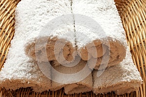 White clean rolled terry towel stack on wicker basket background. Close up