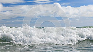 White clean sea waves of tropical beach with blue sky and clouds in colorful sunny day. Scene of summer vacation and holiday