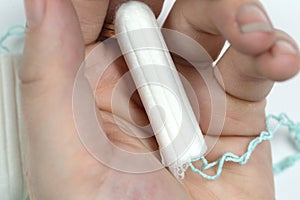 White clean tampon on woman`s hand isolated on a white background. Menstruation time. Hygiene and protection.
