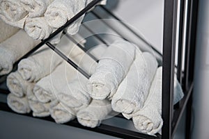 White clean towels rolled up on a roll are stored on shelves in a beauty salon in a barbershop spa