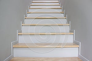 A white clear stairs over the grey wall.