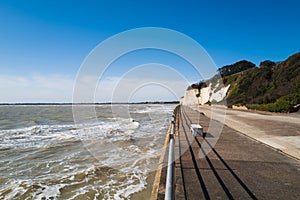 White cliffs  at the end of a promenade on a sunny but windy spring day with blue sky and shadows