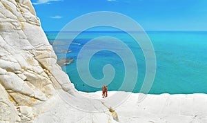 White cliffs naturally made of smooth pug at Scala dei Turchi beach with group of young people and turquoise mediterra photo