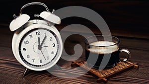 White clock 12 O`clock with coffee cup on wood background.