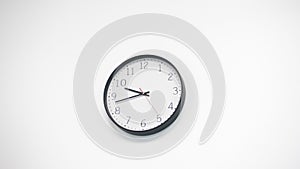 A white clock hangs on a white wall. The clock that goes by shows the exact time. Frame moves