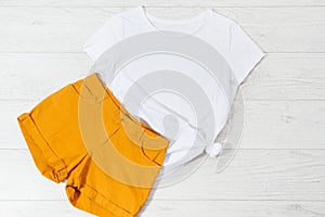 White closeup t shirt mock up flat lay on white wooden background. Top view and copy space. Mockup summer t-shirt and summertime.