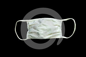A white cloth face mask is isolated on a black background