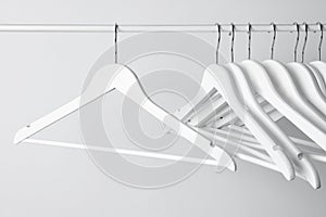 White clothes hangers on metal rail against light background