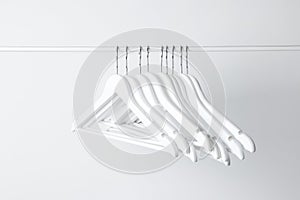 White clothes hangers on metal rail against light background