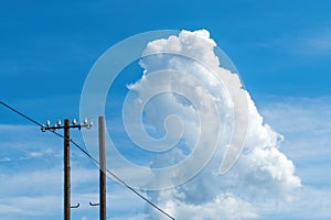 White cloud at the sky, over the old wooden electricity post and wires