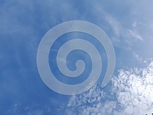 White clouds in the blue sky. Beautiful bright blue background. Light cloudy, good weather. Curly clouds on a sunny day.