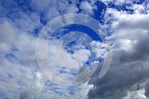 White clouds in the blue sky. Natural summer background. Thickening of rain clouds in one place