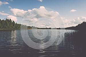 White clouds on the blue sky over blue lake - retro vintage effect