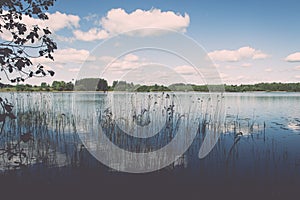 White clouds on the blue sky over blue lake - retro vintage effect