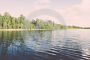 White clouds on the blue sky over blue lake - retro vintage effect