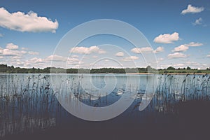 White clouds on the blue sky over blue lake - retro vintage effect