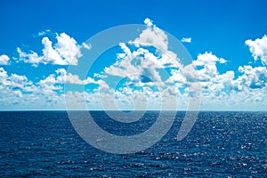 White clouds in blue sky over bright sparkling water of North Atlantic Ocean
