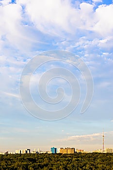 White clouds in blue sky over city park at sunset