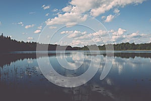 White clouds on the blue sky over blue lake - retro vintage effect