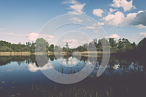 White clouds on the blue sky over blue lake - retro vintage effect