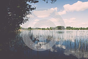 White clouds on the blue sky over blue lake - retro vintage effect