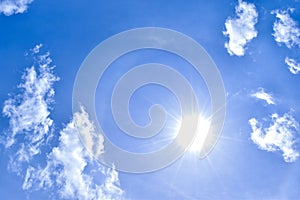 White clouds and blue sky with the sun on midday.